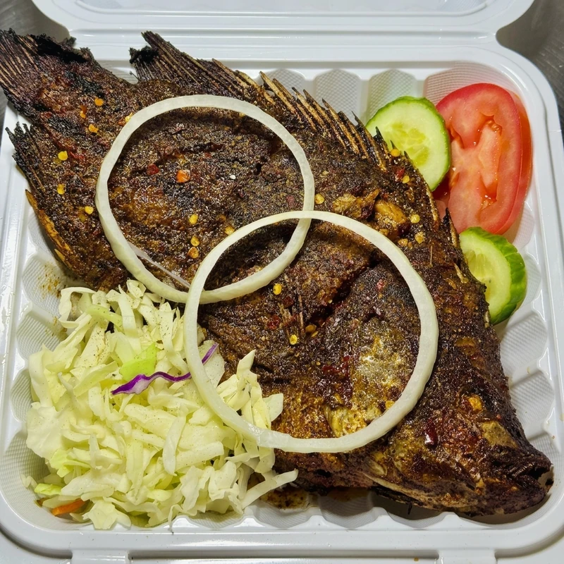 Whole Nigerian grilled fish with coleslaw at Lagos Flavors in Queen Mary Park, Edmonton, AB