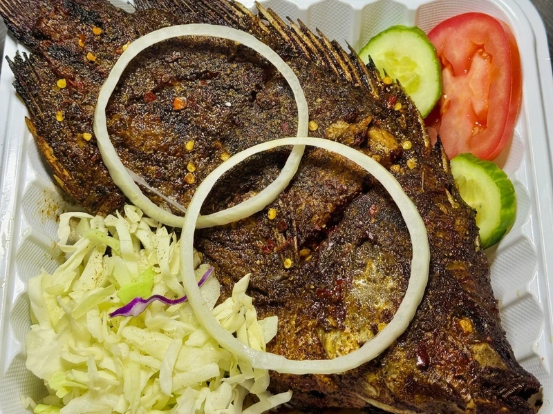 Whole Nigerian grilled fish with coleslaw at Lagos Flavors in Queen Mary Park, Edmonton, AB